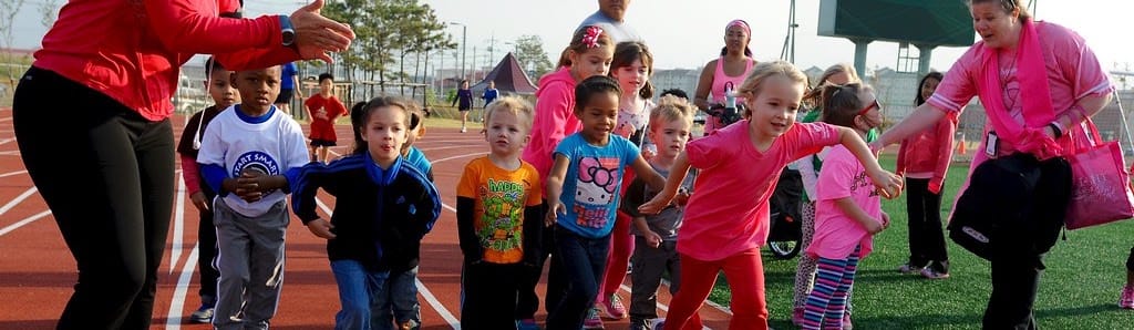Bambini delle elementari che corrono in pista insieme agli istruttori