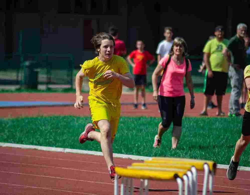 Ragazzo in maglia gialla che corre verso gli ostacoli bassi